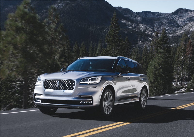 A 2023 Lincoln Aviator® Grand Touring SUV being driven on a winding road to demonstrate the capabilities of all-wheel drive | Libertyville Lincoln Sales, Inc. in Libertyville IL