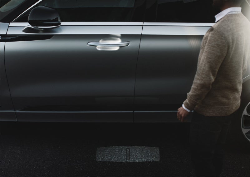A person approaches a 2023 Lincoln Aviator® Grand Touring SUV as the Lincoln Embrace sequence of welcome lighting illuminates | Libertyville Lincoln Sales, Inc. in Libertyville IL