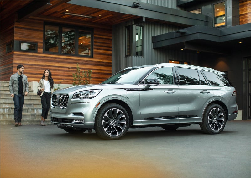 A couple approach a 2023 Lincoln Aviator® Grand Touring model parked in the driveway of a modern home | Libertyville Lincoln Sales, Inc. in Libertyville IL