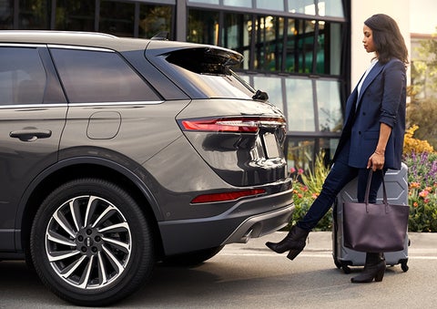 A woman with her hands full uses her foot to activate the hands-free liftgate. | Libertyville Lincoln Sales, Inc. in Libertyville IL