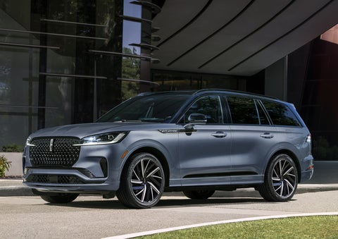 A gray 2025 Lincoln Aviator® SUV is parked outside a modern building showcasing the driver’s side of the vehicle. | Libertyville Lincoln Sales, Inc. in Libertyville IL