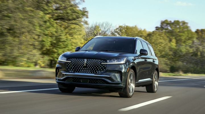 A 2025 Lincoln Black Label Aviator® SUV is being driven down a road lined with trees. | Libertyville Lincoln Sales, Inc. in Libertyville IL