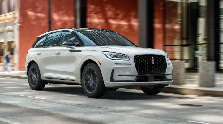 A white 2025 Lincoln Corsair® SUV with the Jet Appearance Package is being driven through a city.| Libertyville Lincoln Sales, Inc. in Libertyville IL
