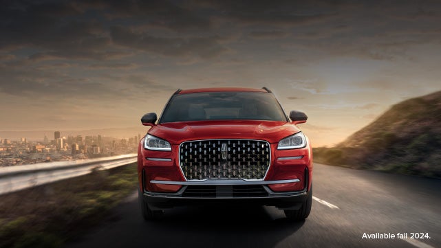 A 2025 red Lincoln Corsair® SUV is being driven down a road at sunset. | Libertyville Lincoln Sales, Inc. in Libertyville IL