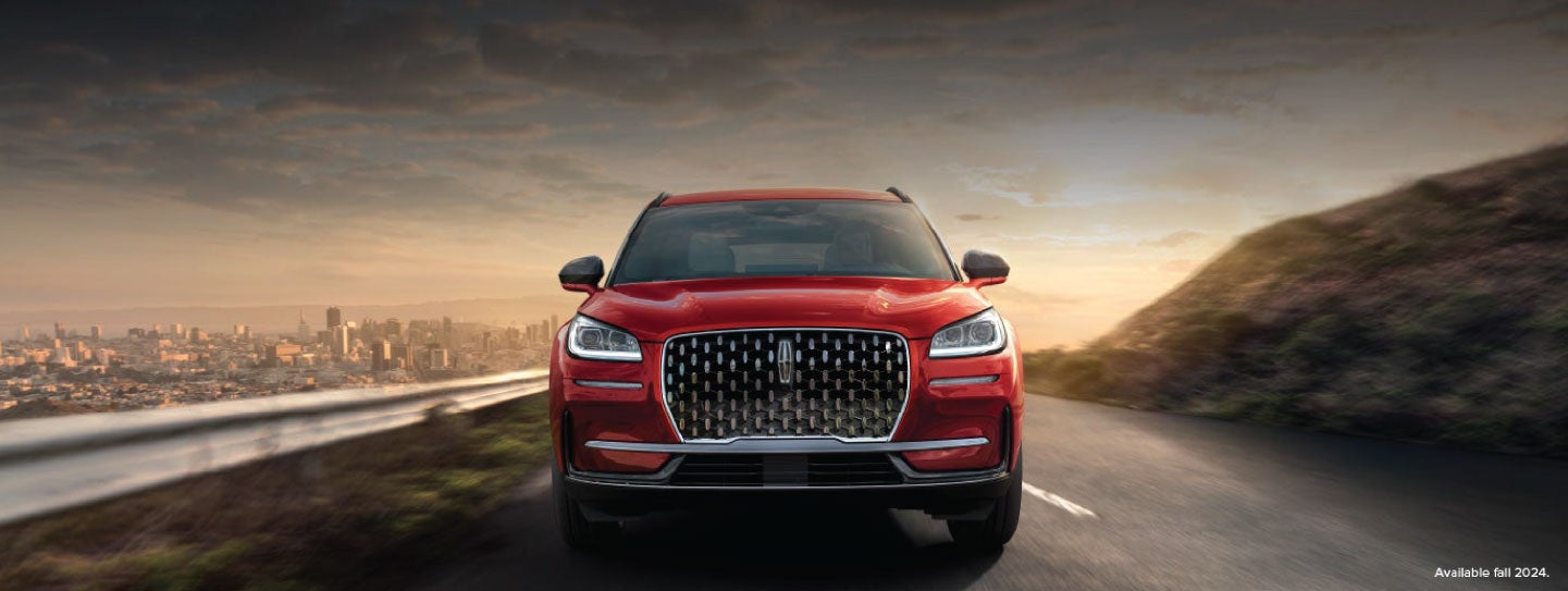 A 2025 red Lincoln Corsair® SUV is being driven down a road at sunset. | Libertyville Lincoln Sales, Inc. in Libertyville IL