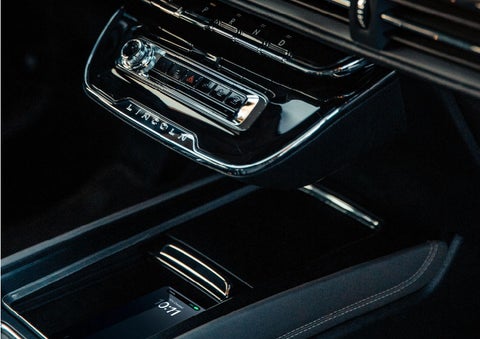 A smartphone is is being placed on the wireless charging pad in the front center console cubby. | Libertyville Lincoln Sales, Inc. in Libertyville IL