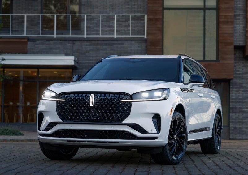 A 2026 Lincoln Aviator® Reserve model is shown with the available Jet Appearance Package parked near a restaurant. | Libertyville Lincoln Sales, Inc. in Libertyville IL