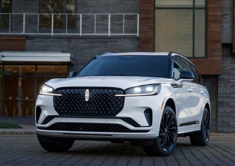 A 2026 Lincoln Aviator® Reserve model is shown with the available Jet Appearance Package parked near a restaurant. | Libertyville Lincoln Sales, Inc. in Libertyville IL