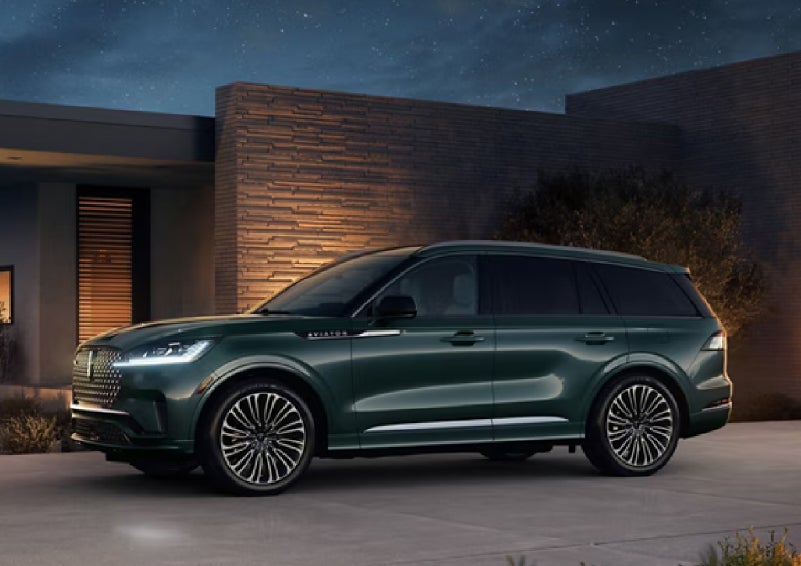 A green 2027 Lincoln Aviator® SUV is parked outside a contemporary home. | Libertyville Lincoln Sales, Inc. in Libertyville IL