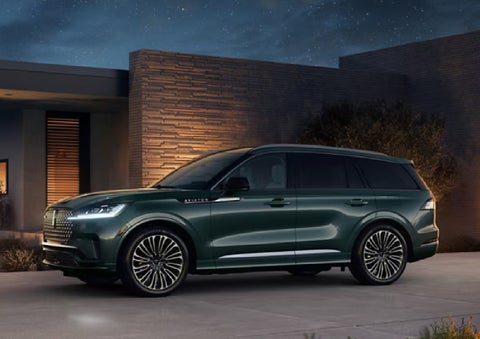 A green 2027 Lincoln Aviator® SUV is parked outside a contemporary home. | Libertyville Lincoln Sales, Inc. in Libertyville IL