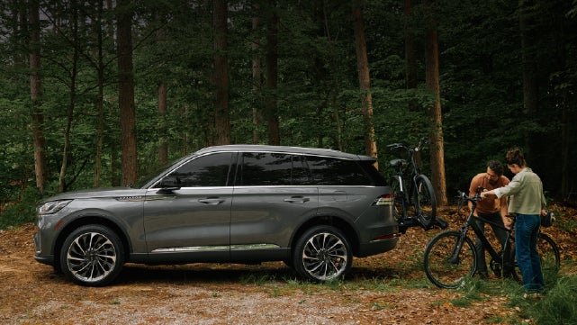 A father and son load e-bikes on a bike rack attached to a 2027 Lincoln Aviator® SUV. | Libertyville Lincoln Sales, Inc. in Libertyville IL