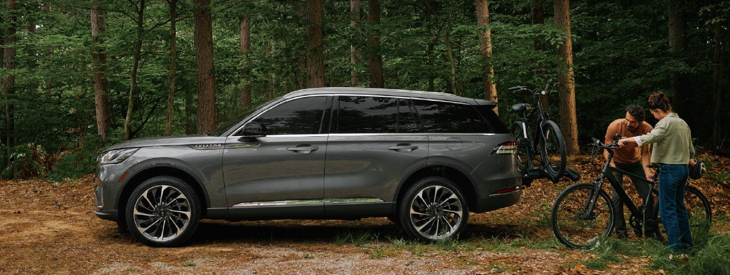 A father and son load e-bikes on a bike rack attached to a 2027 Lincoln Aviator® SUV. | Libertyville Lincoln Sales, Inc. in Libertyville IL